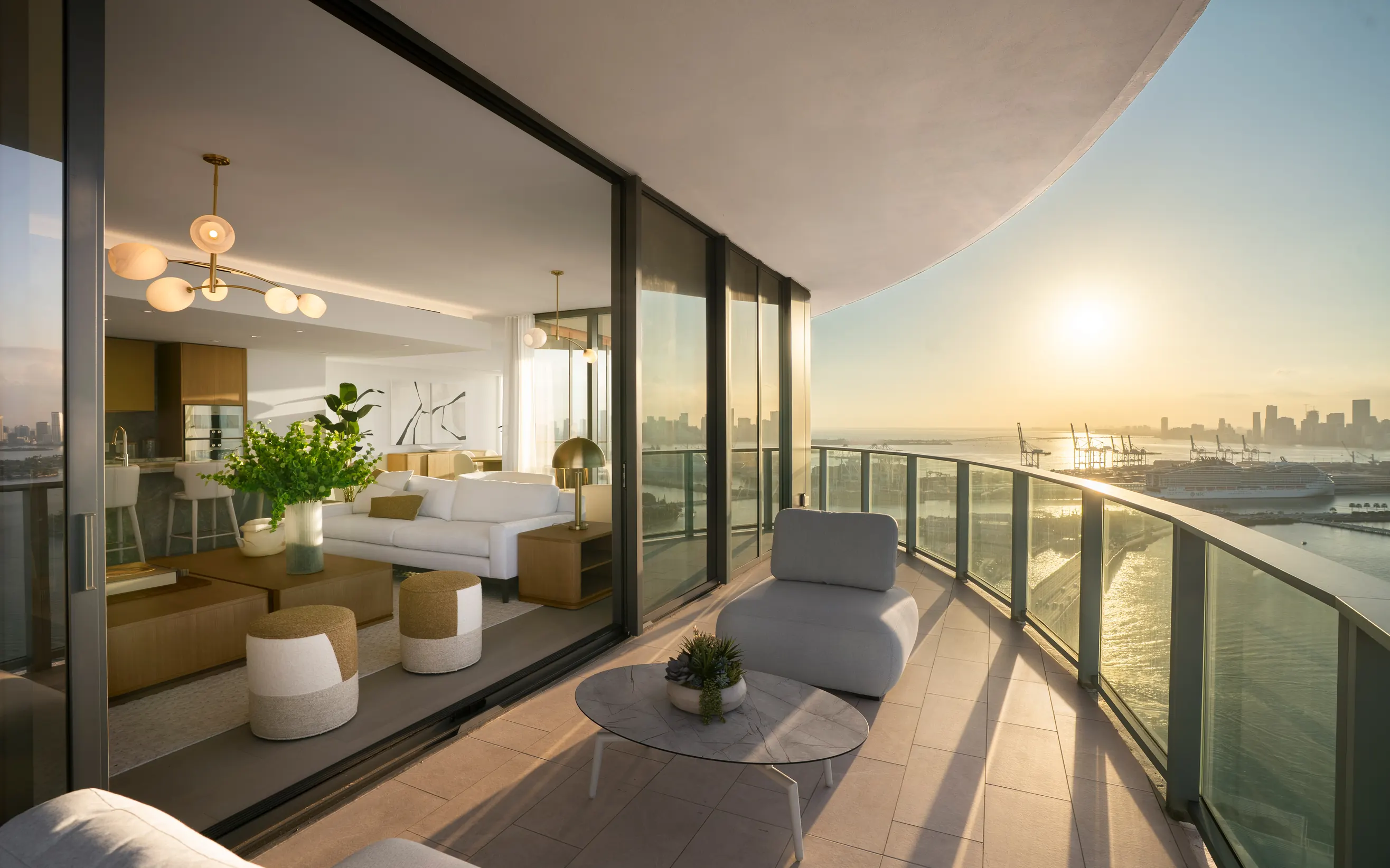 A Five Park living room opening onto a curved terrace at sunset, the Miami skyline across the bay